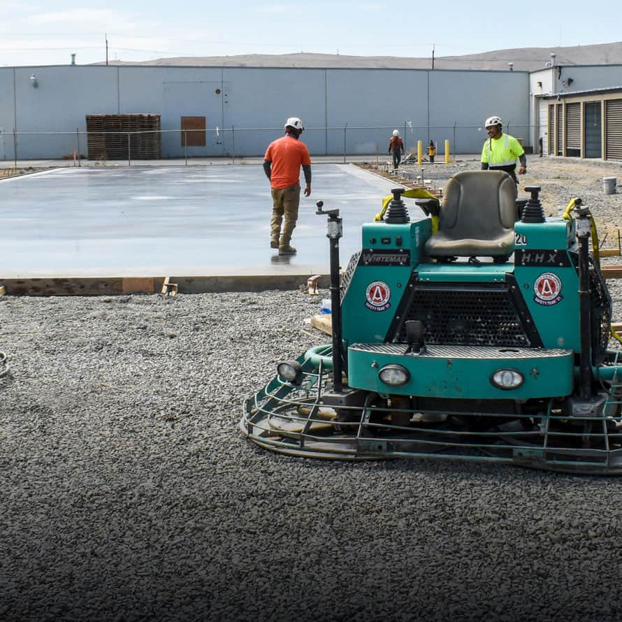 A trowel machine in front of a storage facility slab of concrete