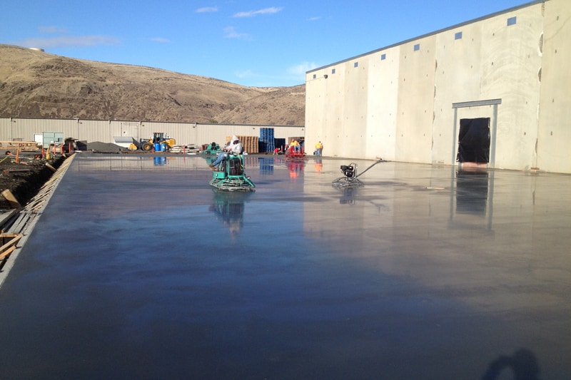 Concrete slab floor being smoothed by trowel machine