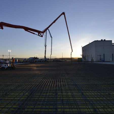 Concrete pumps at slab job site with sunset