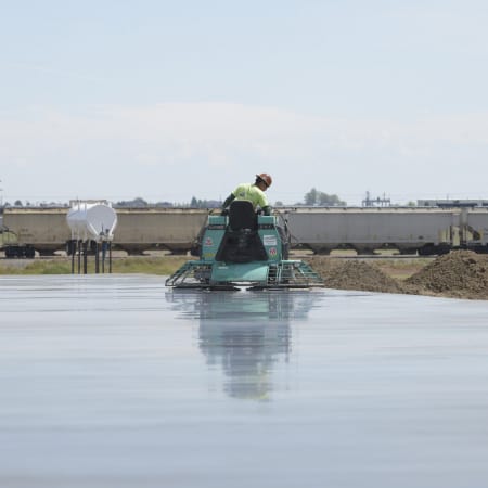 Poppoff worker smoothing concrete slab floor