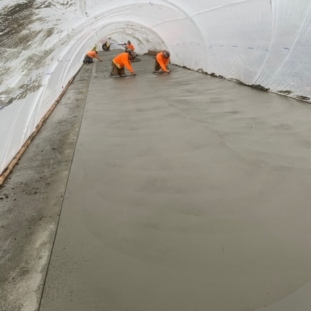 Concrete contractors smoothing concrete slab inside rain tunnel