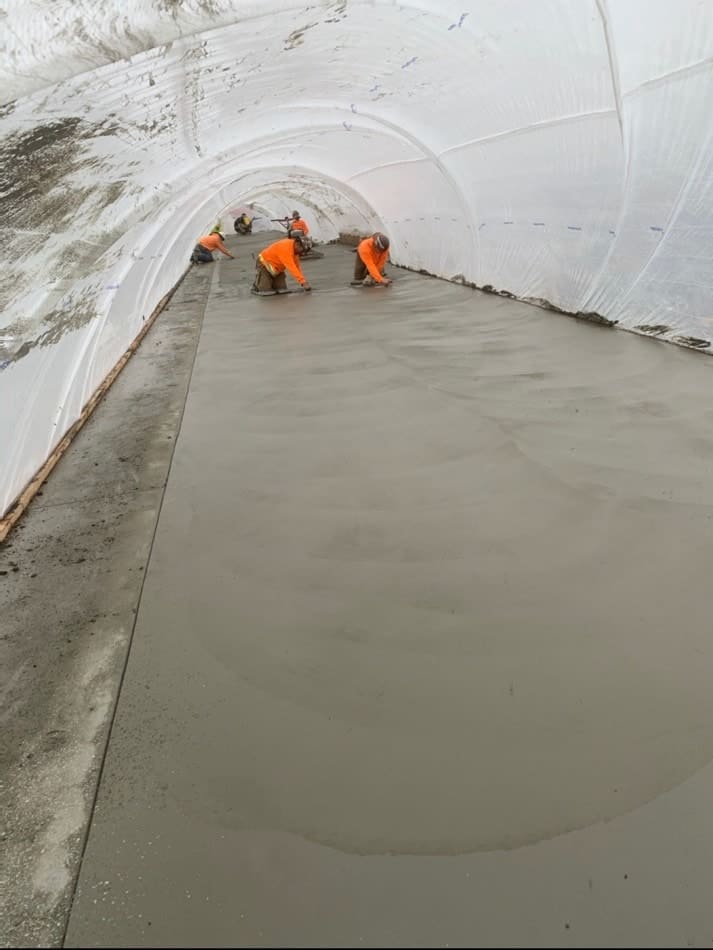 Concrete contractors smoothing concrete slab inside rain tunnel