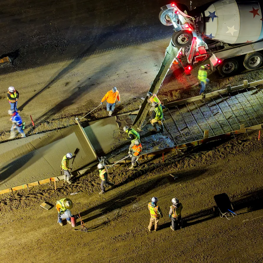 Overhead view of concrete truck pouring concrete into forms with steel rebar